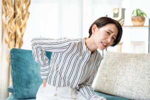 ソファに座って腰を押さえる女性