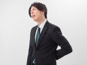 腰を押さえるスーツ姿の男性