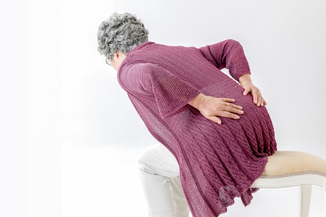 前かがみで腰を押さえる高齢の女性