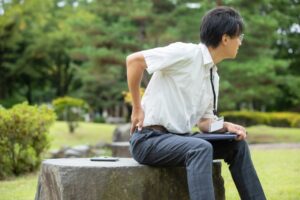 公園のベンチで腰を押さえる男性